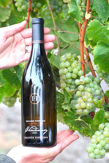 Bottle of our Chardonnay from Balletto Vineyard grapes against the backdrop of the 2023 harvest.