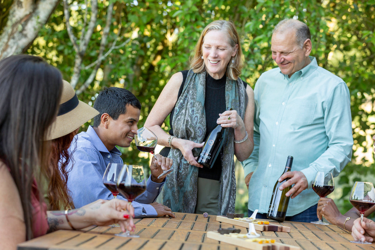 Visitors indulge in a tasting experience at a renowned Sonoma winery, immersed in the scenic beauty of a picturesque vineyard. The winery showcases an impressive selection of wines, including exquisite Pinot Noirs, crafted from sustainably grown wine grapes sourced from single-vineyard sites. Guests can explore the diverse vintages and discover their passion for red wines in the inviting ambiance of the winery and its adjacent wine shop.